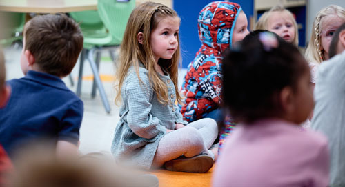 Preschoolers sitting on the floor listening to their inspiring teacher