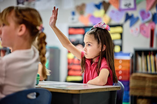 A young Scholar raising her hand during class at Leman Academy in Sierra Vista